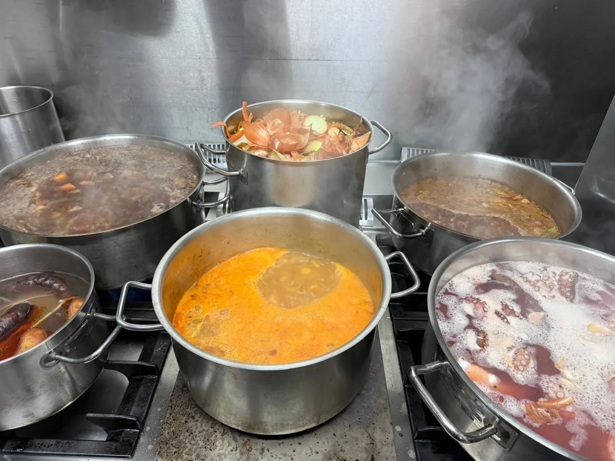 Tachos a borbulhar na cozinha do Fogo e Tradição com caldos dourados