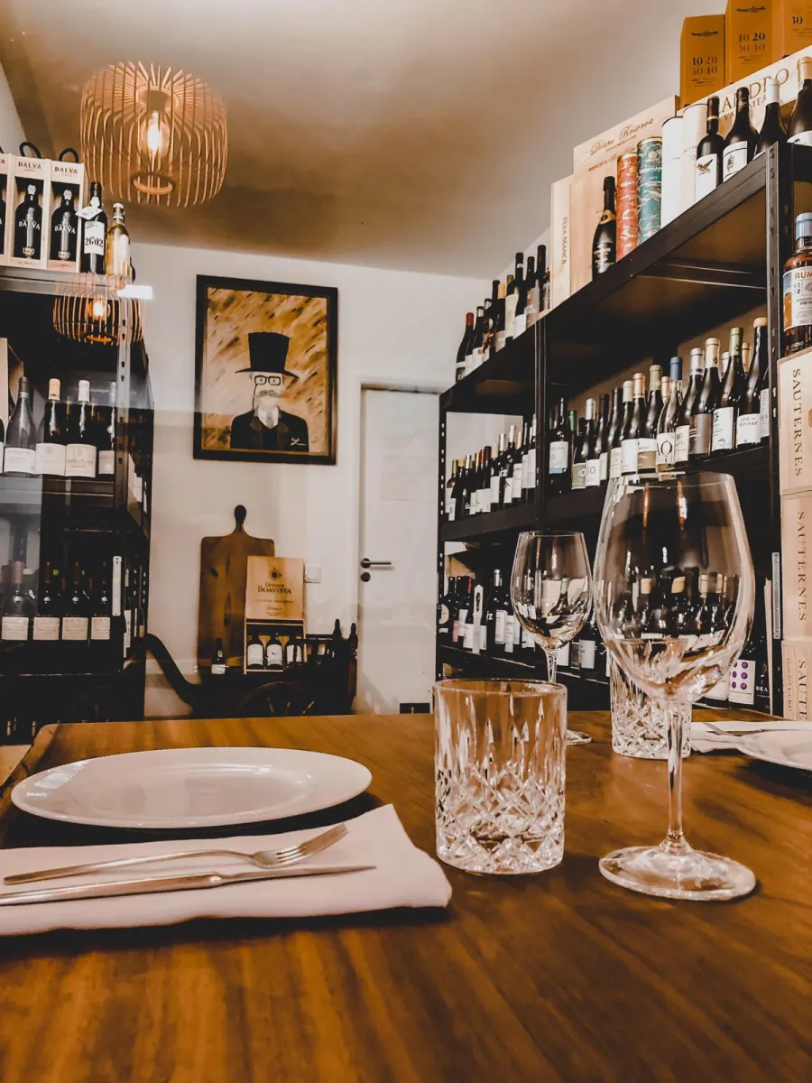 Mesa na garrafeira do Fogo e Tradição com copos de cristal e garrafas de vinho
